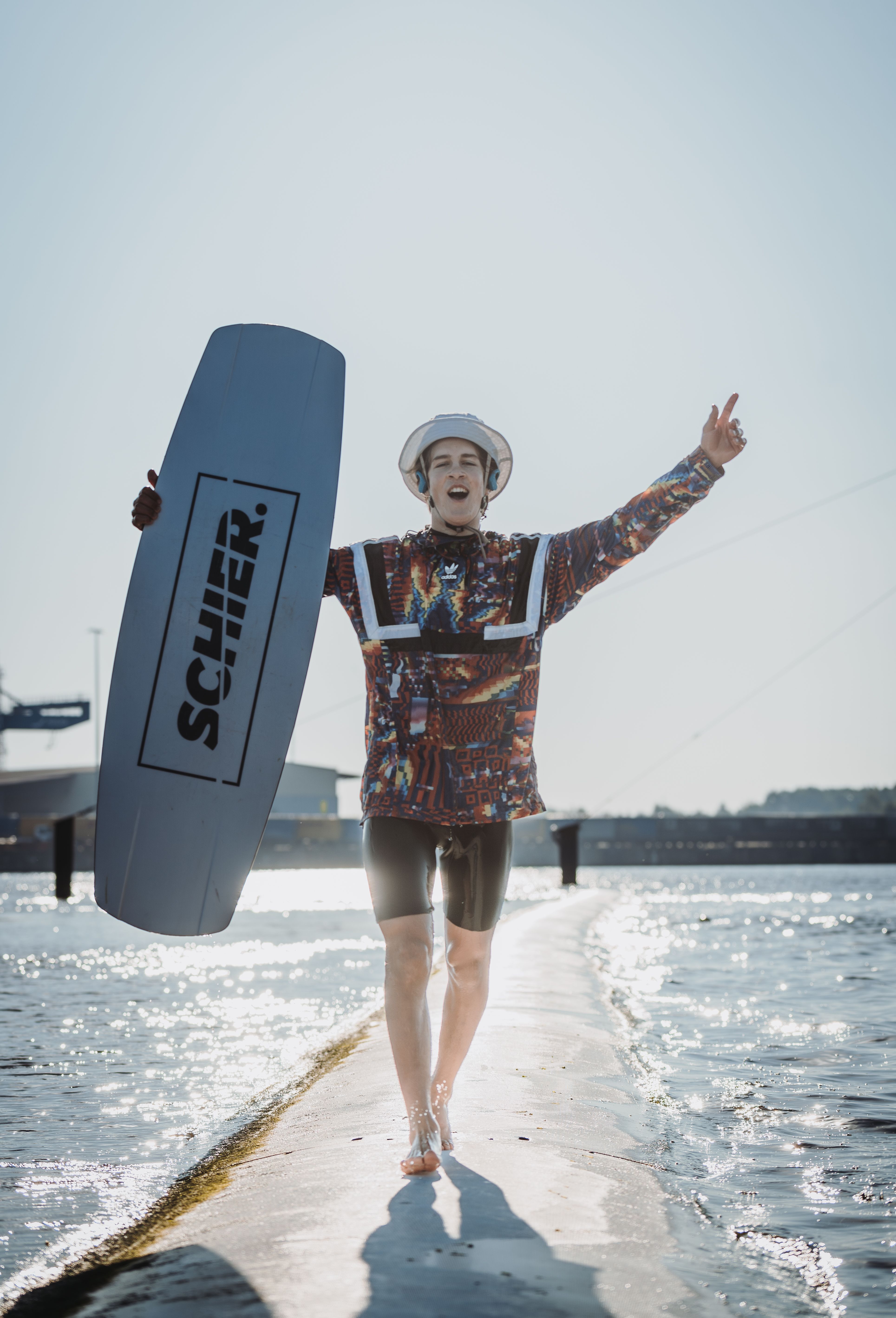 Wakeboarder läuft mit Board über den Steg